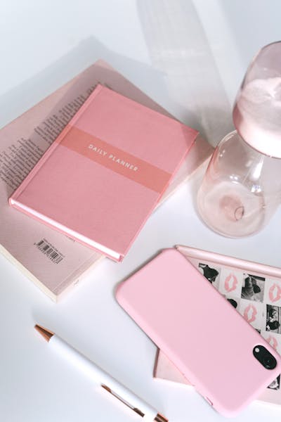 Pink Smartphone and a Planner over White Surface